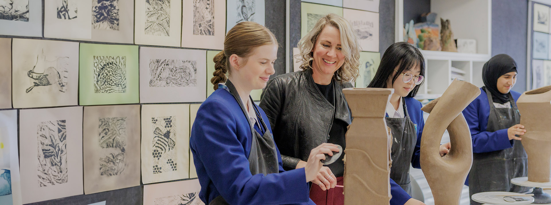 Caroline Chisholm Catholic College Glenmore Park teacher assisting students in art class. The students are sculpting