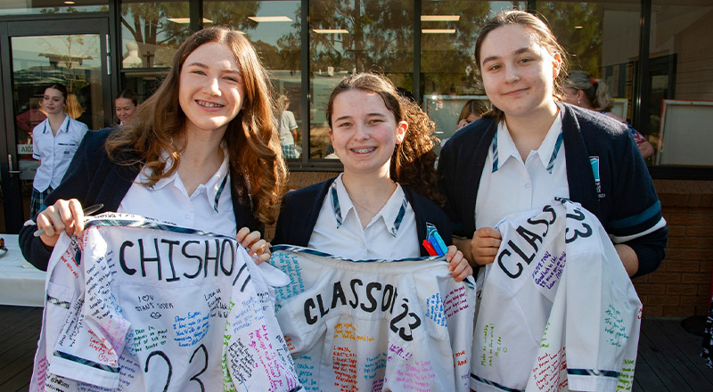 Caroline Chisholm Catholic College Glenmore Park students holding signed uniforms